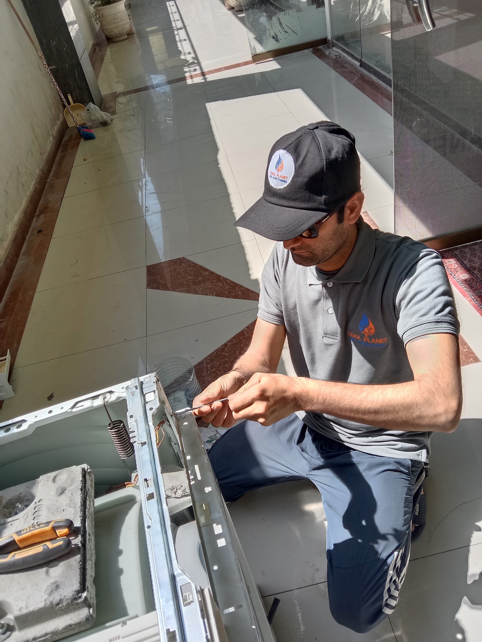 Cool Planet technician repairing a washing machine on the floor