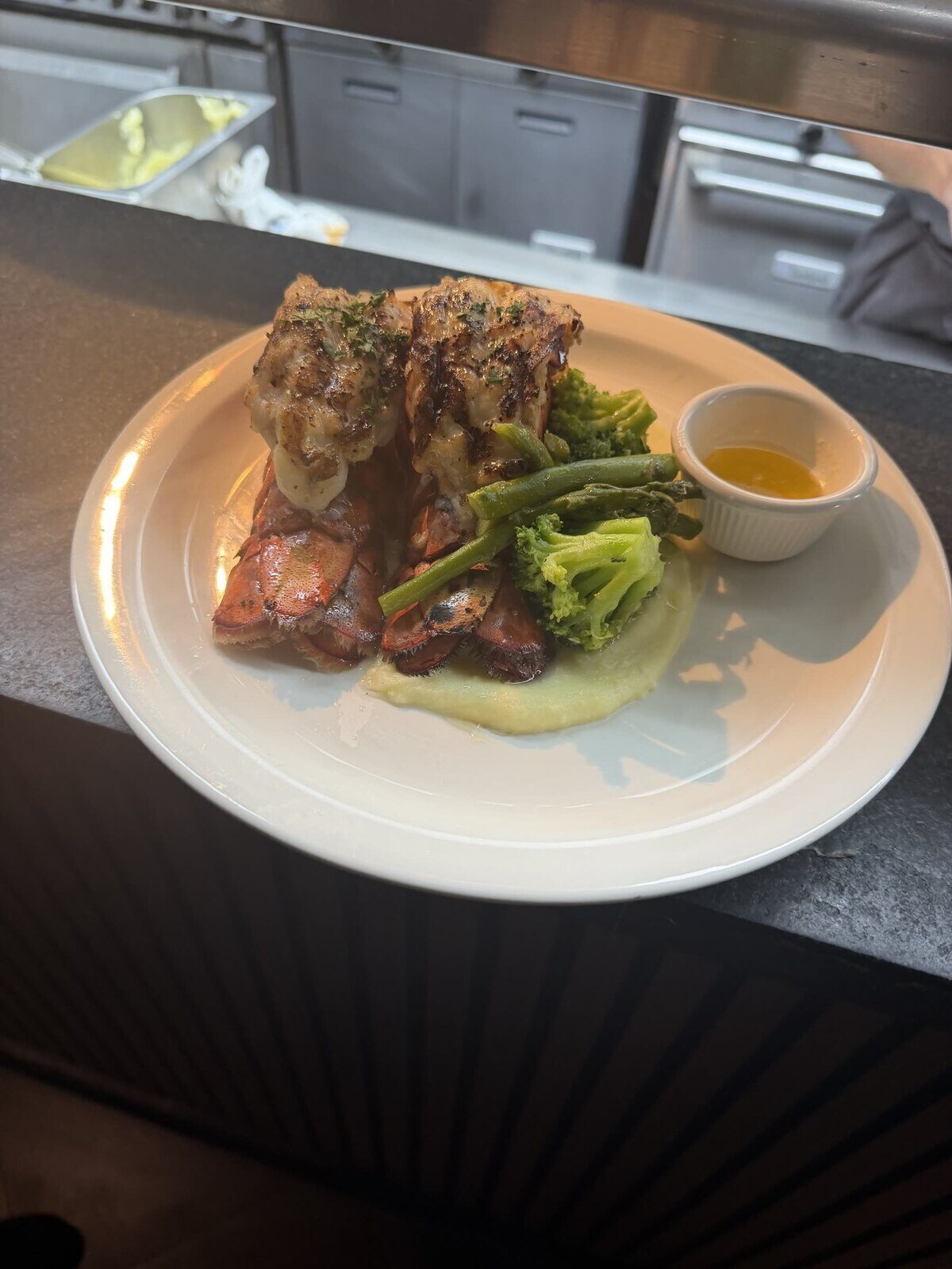 Grilled lobster tails with asparagus, mashed potato, and drawn butter